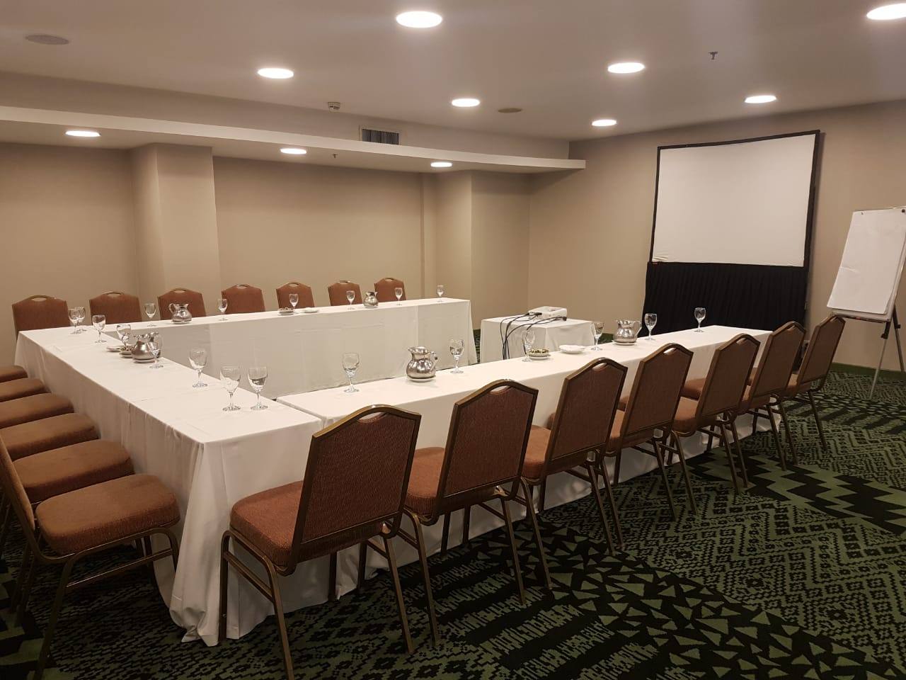 Salón del Hotel Sheraton Salta con mesas, sillas y pantalla
